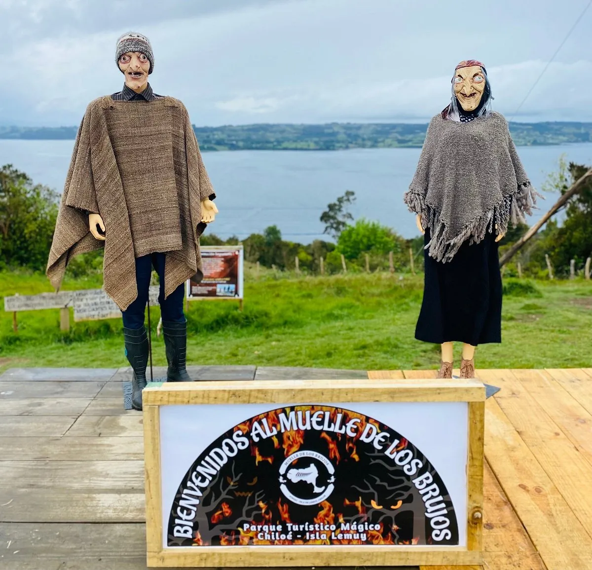 Figuras de un brujo y una bruja junto al letrero de bienvenida al Muelle de los Brujos