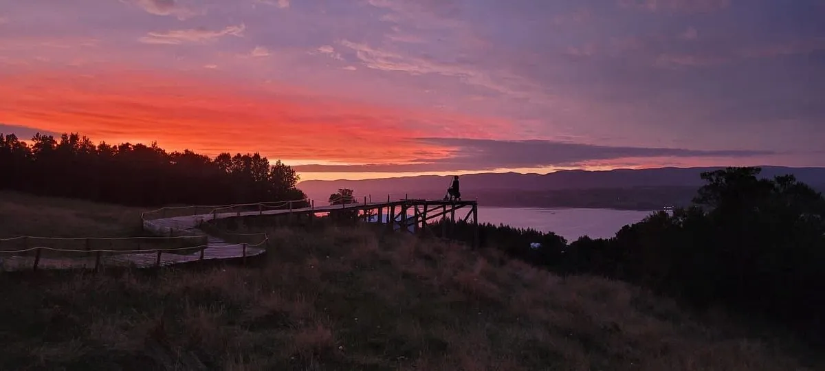 Pasarela del mirador al atardecer, con el cielo rojo sobre el canal